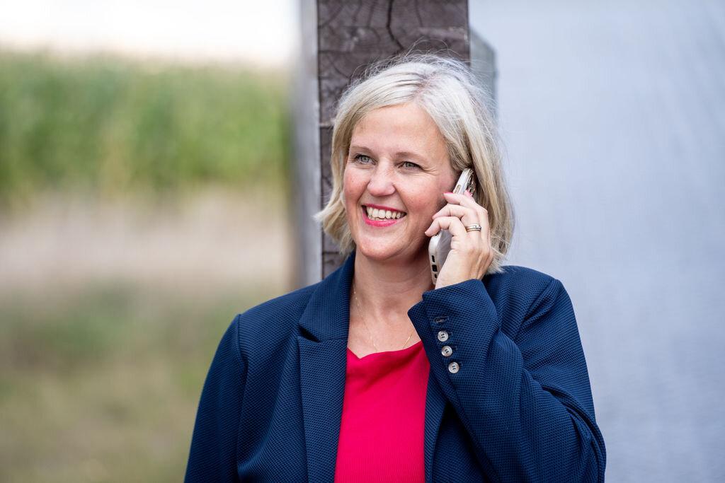 Hester Wijenberg aan de telefoon, in een donkerblauw jasje